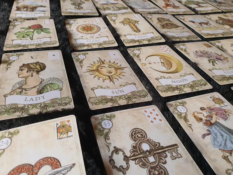 Old Style Lenormand on a dark cloth, showing symbols and playing-card insets.
