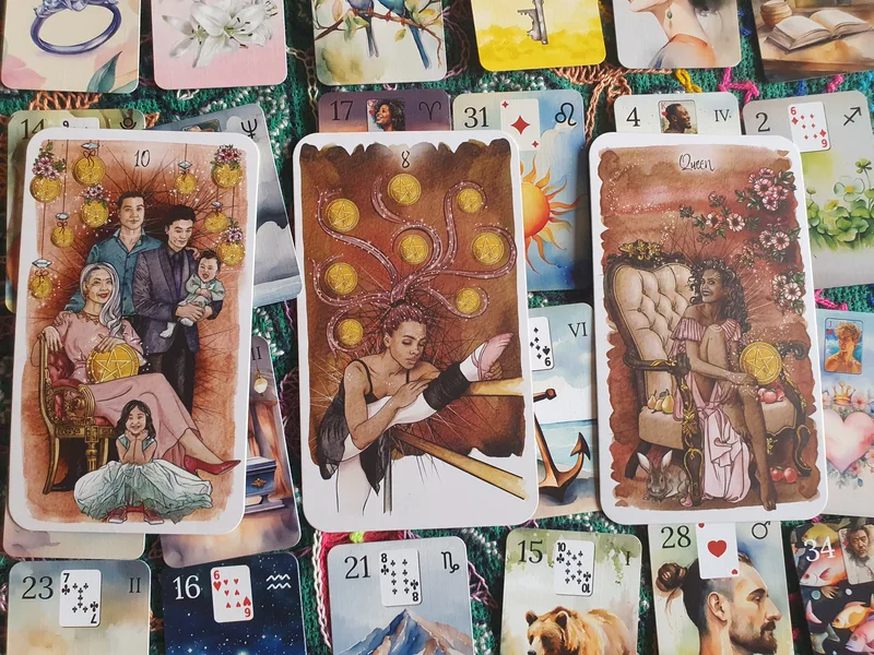 Ten of Pentacles, Eight of Pentacles and Queen of Pentacles in front of Lenormand cards.