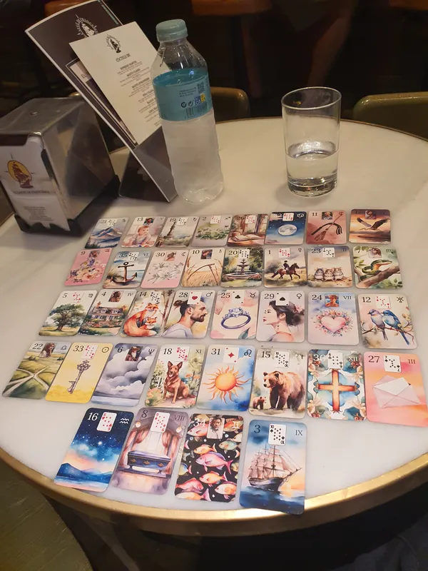 Isabelle’s Aquarelle deck in a Grand Tableau on a round table: four rows of eight, with four cards below.
